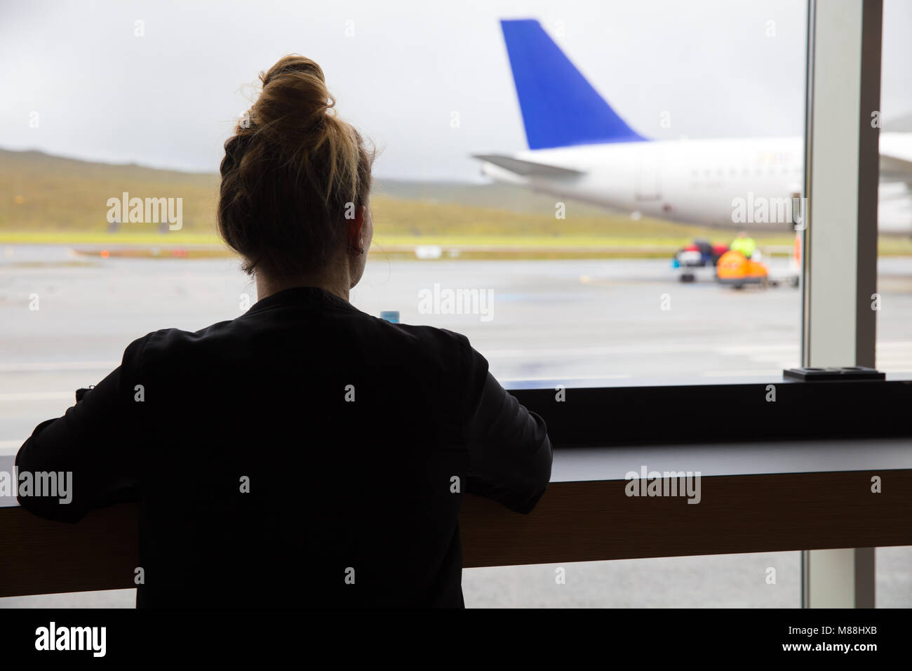 Woman Looking At Airplane Through Window At Airport Stock Photo