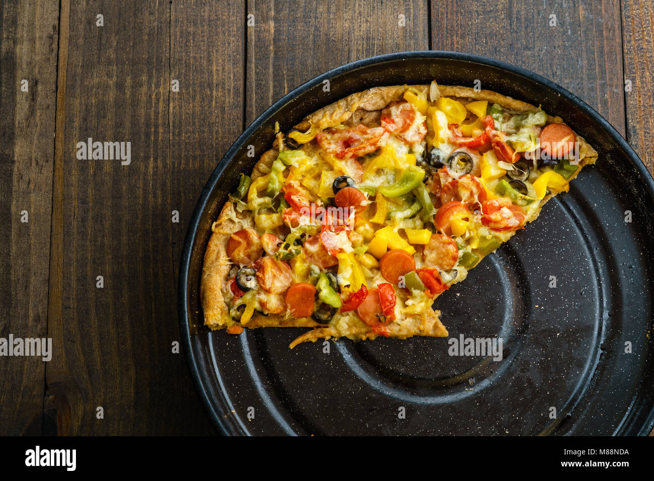 Slices of pizza on metal tray on dark table, from above and blank space. Stock Photo