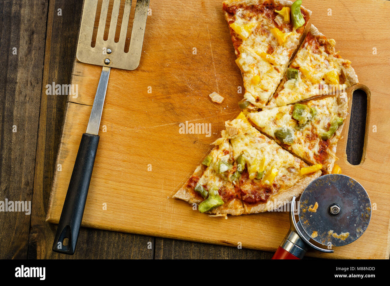 Slices of pizza on wooden board on dark table, from above. Stock Photo