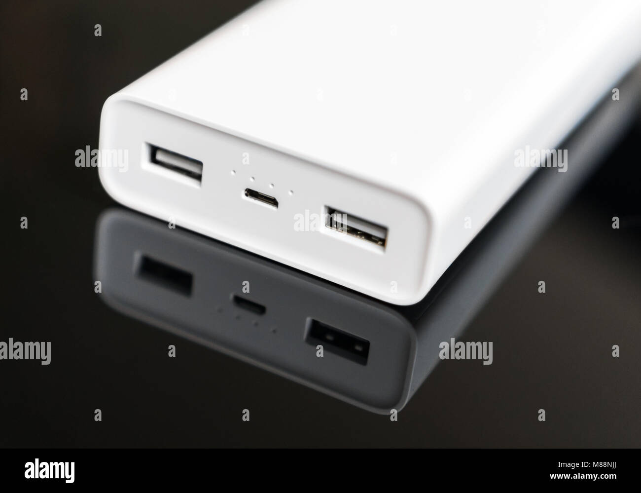 White power bank on mirrored surface. Space for your text. Stock Photo
