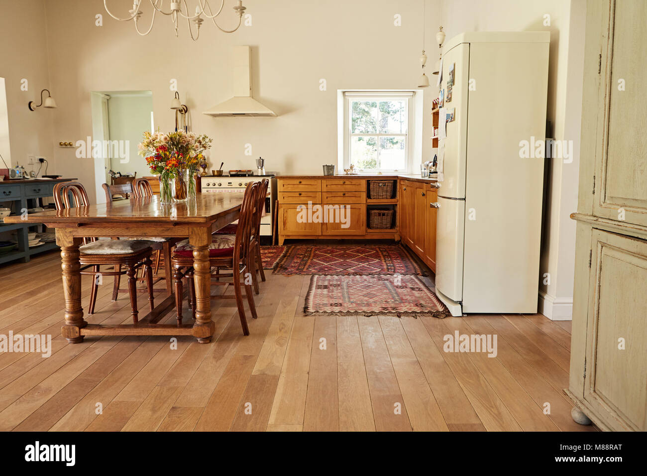 Interior of a country style kitchen in a bright residental home with a dining table, chairs and appliances Stock Photo