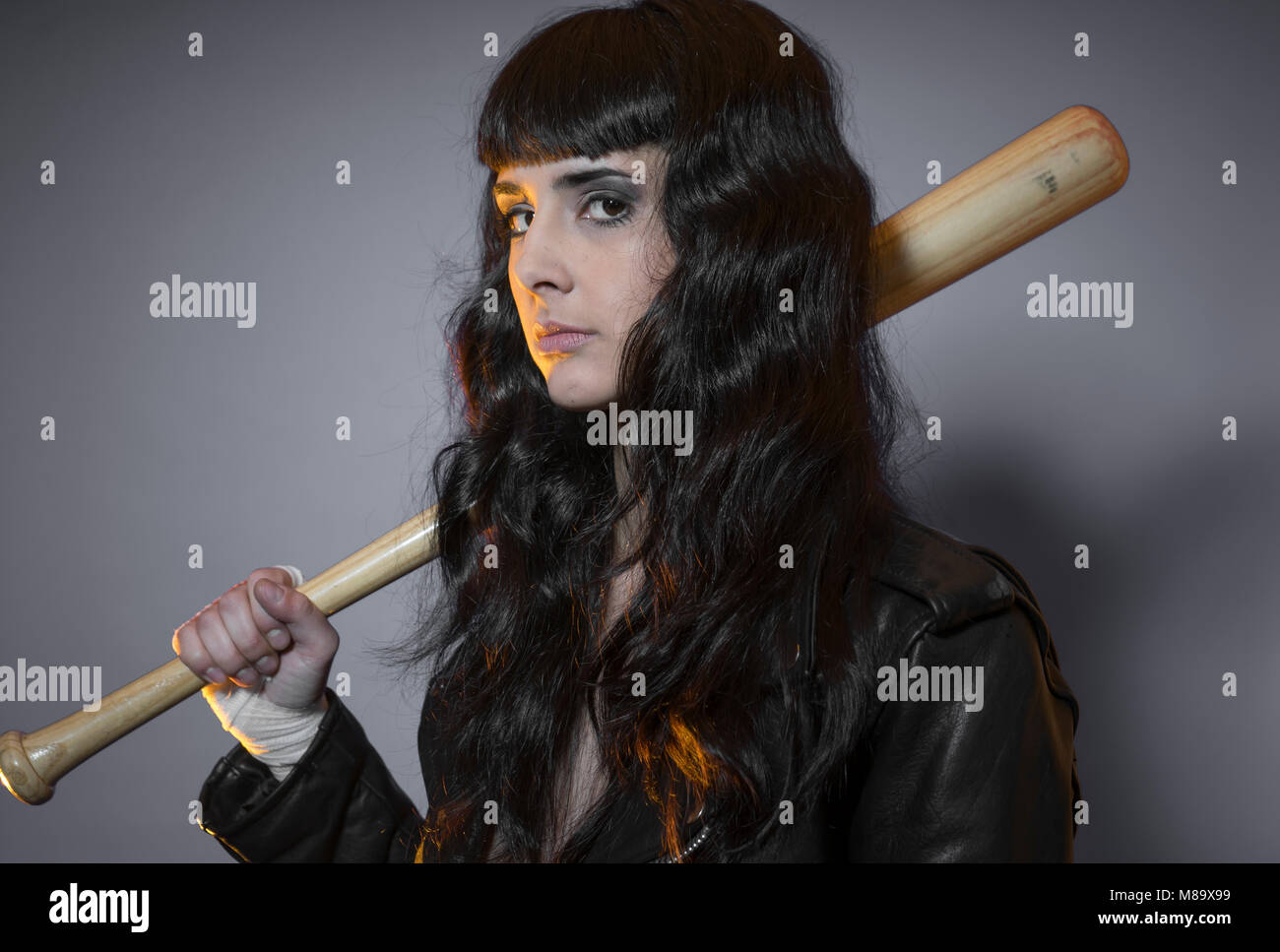 custody, adolescence and delinquency, brunette woman in leather jacket and baseball bat with challenging aptitude Stock Photo