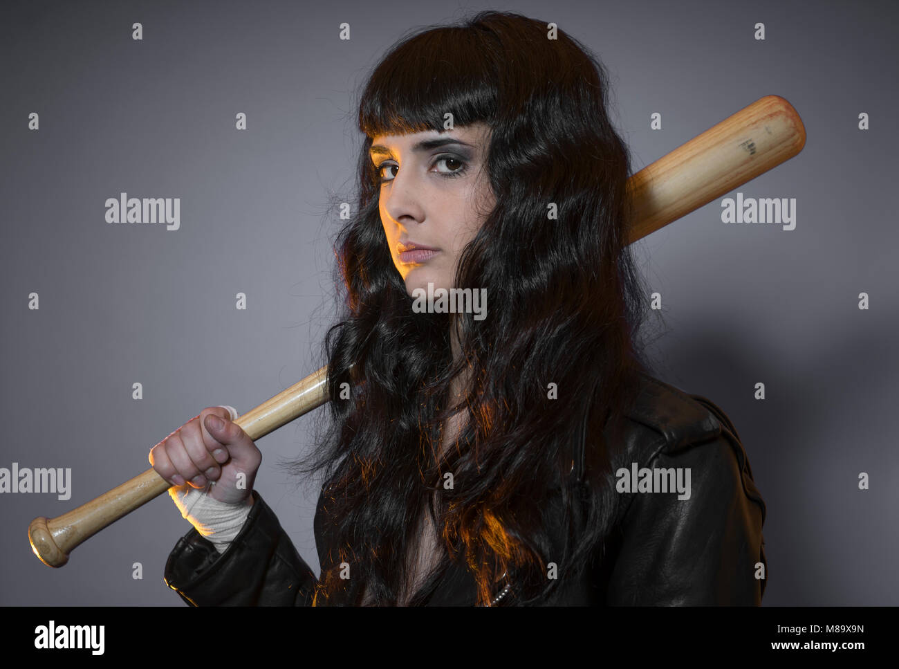 adolescence and delinquency, brunette woman in leather jacket and baseball bat with challenging aptitude Stock Photo