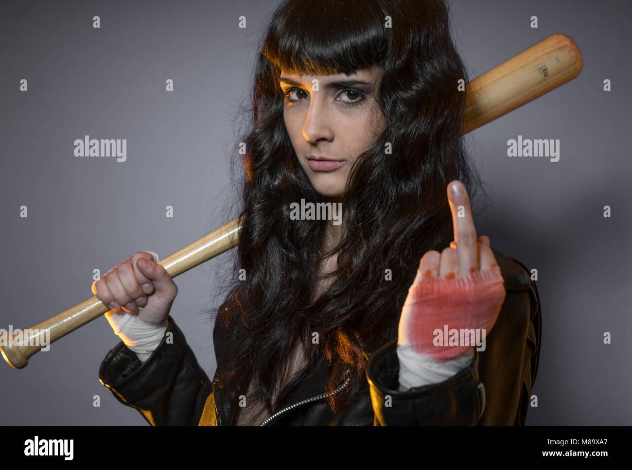 Trouble, adolescence and delinquency, brunette woman in leather jacket and baseball bat with challenging aptitude Stock Photo