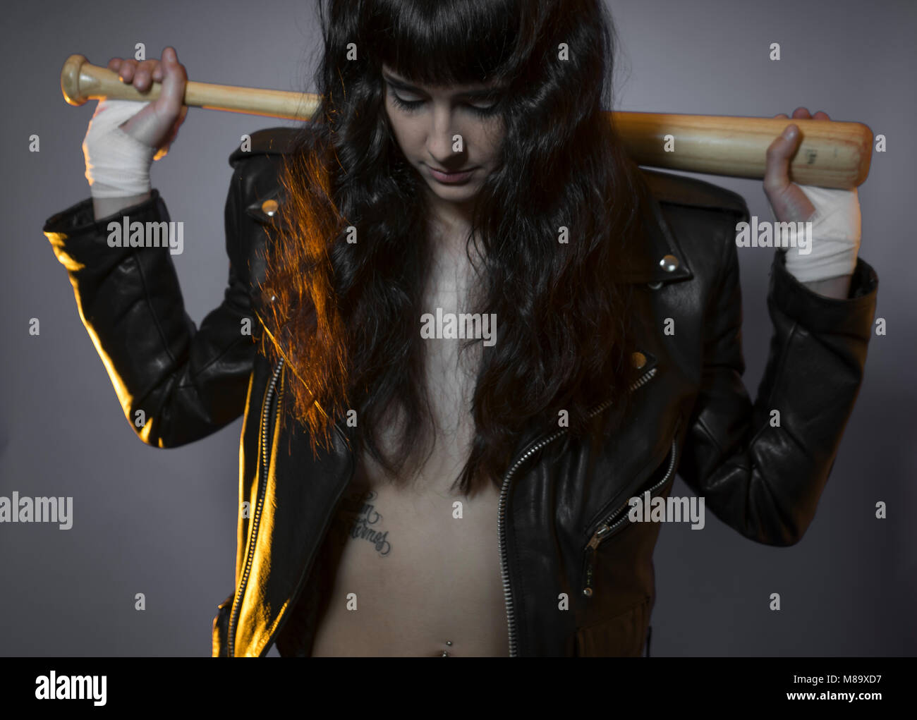 adolescence and delinquency, brunette woman in leather jacket and baseball bat with challenging aptitude Stock Photo