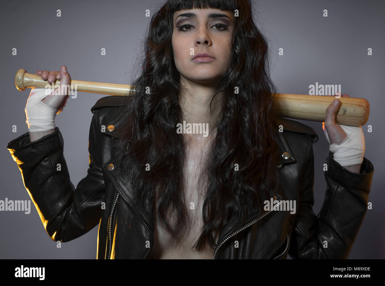 lawbreaker, adolescence and delinquency, brunette woman in leather jacket and baseball bat with challenging aptitude Stock Photo