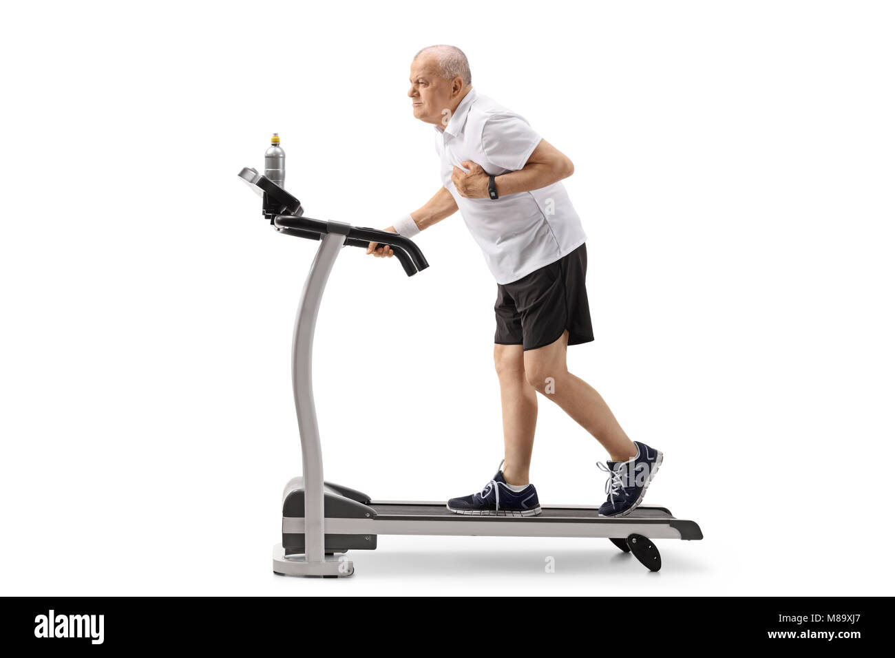 Full length profile shot of a mature man walking on a treadmill and having a heart attack isolated on white background Stock Photo