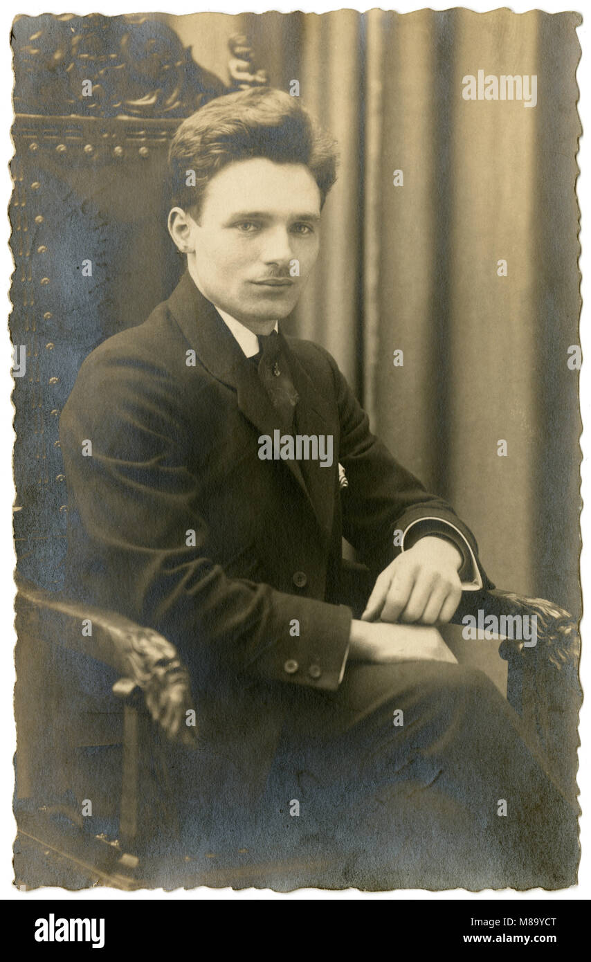 Antique c1920 photograph, 25-year-old man in a fancy library chair. SOURCE: ORIGINAL PHOTOGRAPH. Stock Photo