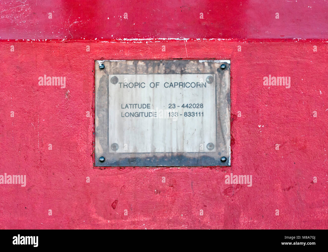 Iconic old rugged metal plate of the Tropic of Capricorn on a red iron background, Australia Stock Photo