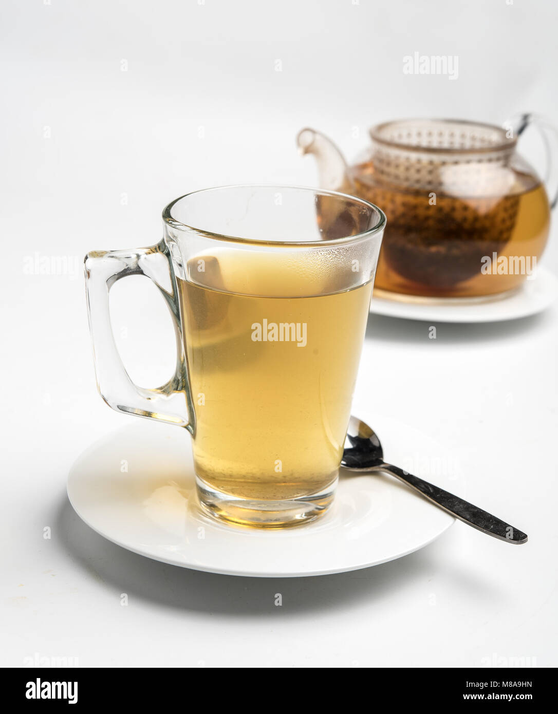 Glass of tea and teapot. The Tea bag can be seen in the pot Stock Photo