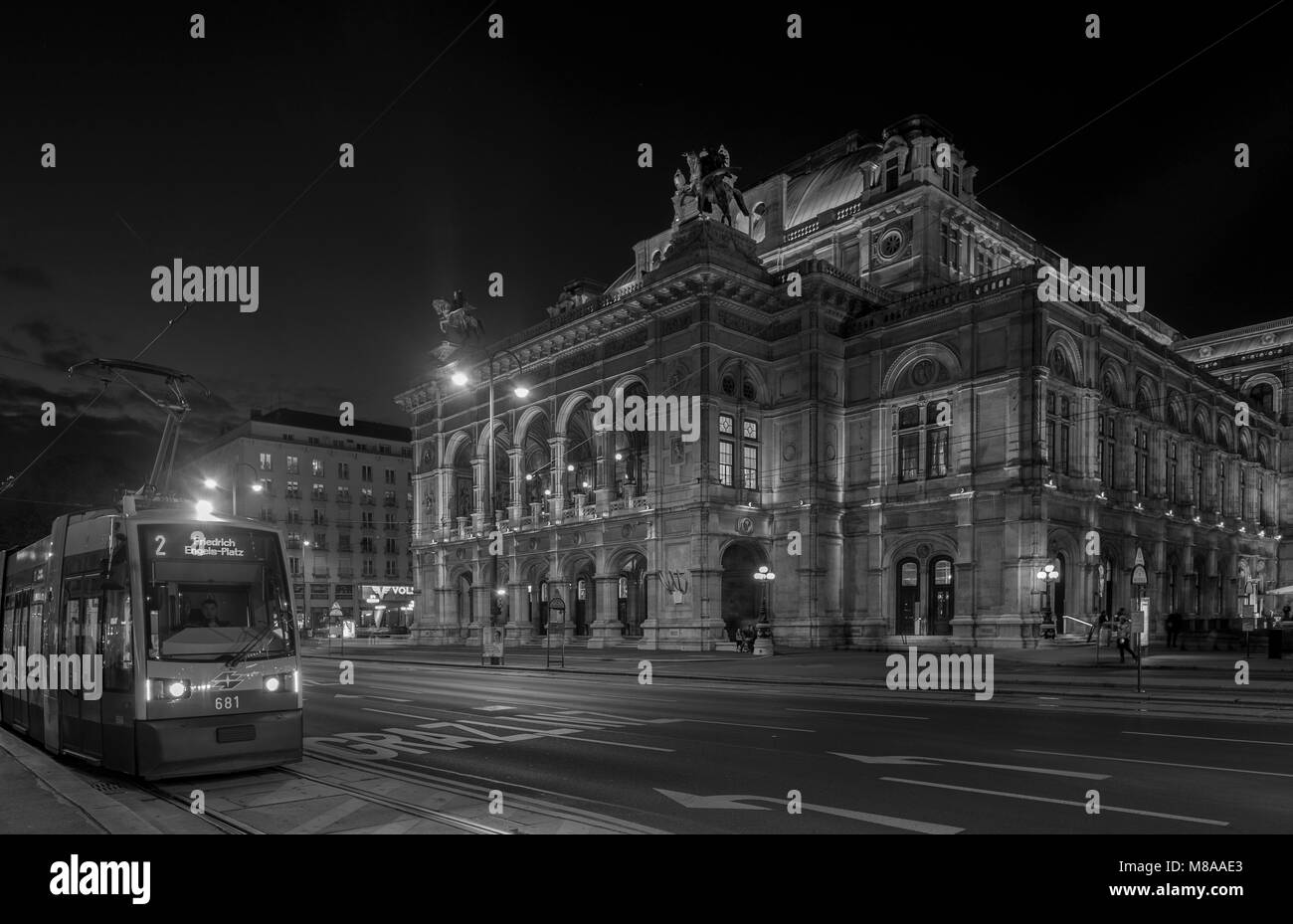 Wide shot of traffic passing in front of the Vienna Opera House on Opernring. Taken early evening in September as the city lights are coming on Stock Photo