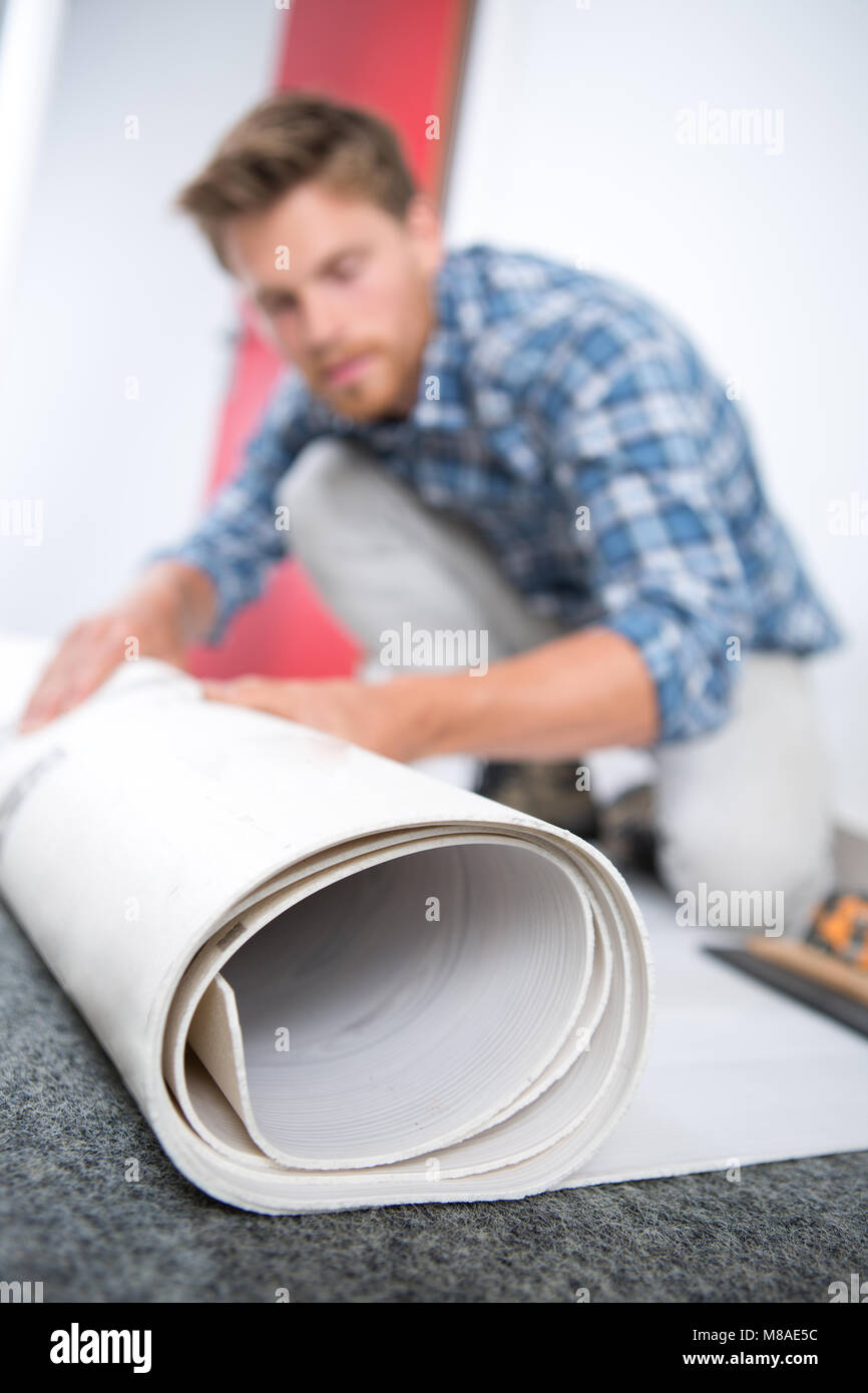 male builder rolling carpet Stock Photo