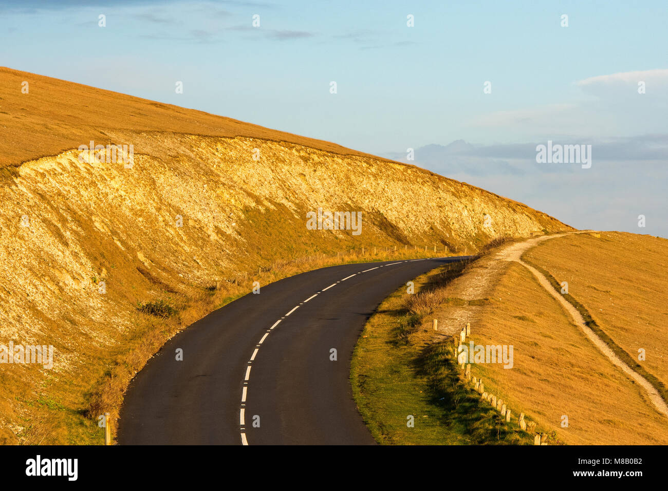 A road on the side or top of a mountain in a cutting through the hills disappearing into the distance and over the horizon.enndless road to nowhere. Stock Photo
