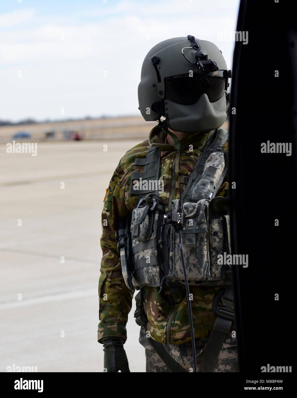 A U.S. Army crew chief with the 1-135th Assault Helicopter Battalion monitors a UH-60 Black Hawk before take off during a joint training at Whiteman Air Force Base, Mo., Jan. 31, 2018. In addition to establishing a partnership, the purpose of the training was to familiarize Joint Terminal Attack Controllers from the 7th Air Support Operations Squadron located in Fort Bliss, Texas, with the assets available at Whiteman AFB that are used in a multi-domain fight. (U.S. Air Force by Staff Sgt. Danielle Quilla) Stock Photo