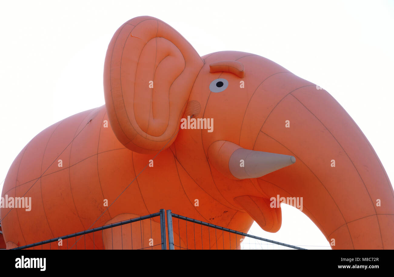 Inflatable pink elephant with white tusks against the blue sky tied ropes Stock Photo