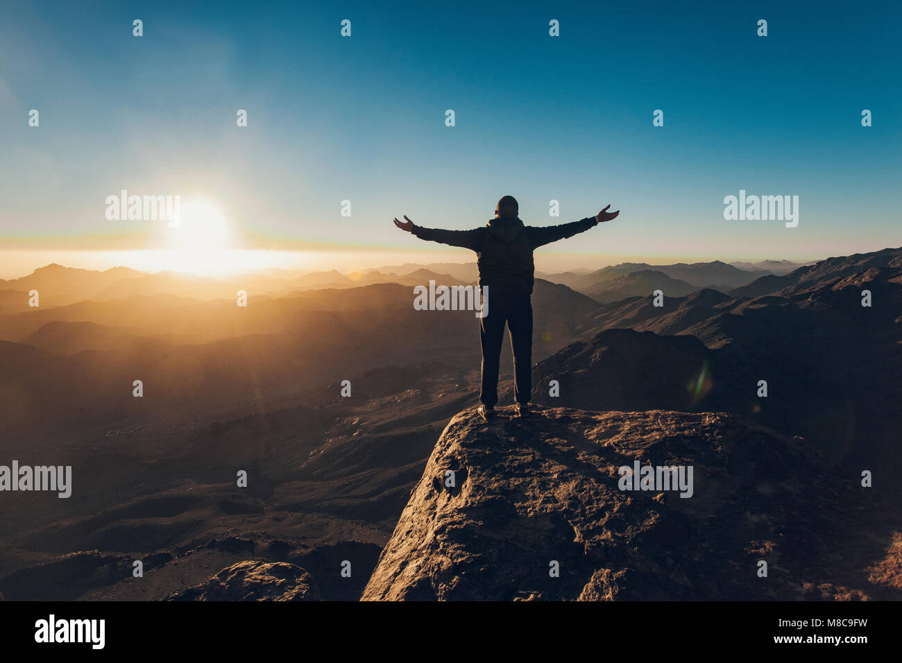 Man stands facing the rising sun and meditates on Mount Sinai in Egypt. Stock Photo