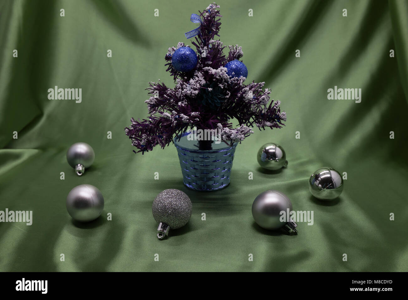 A small Christmas tree in a pot, decorated with balls, garlands and