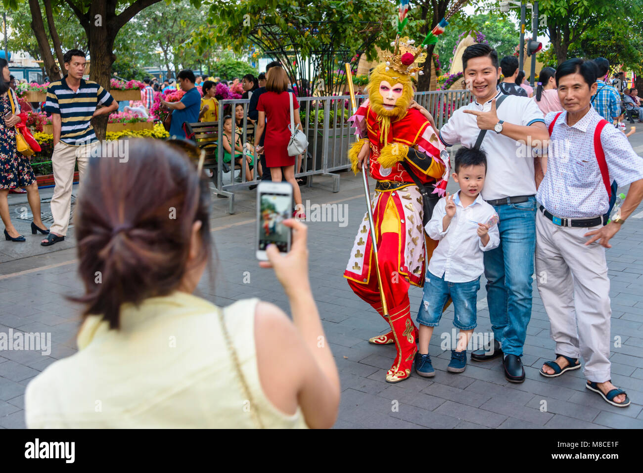 A Group of people have a photograph taken with a man in a traditional monkey costume, Ho Chi Minh City, Saigon, Vietnam Stock Photo