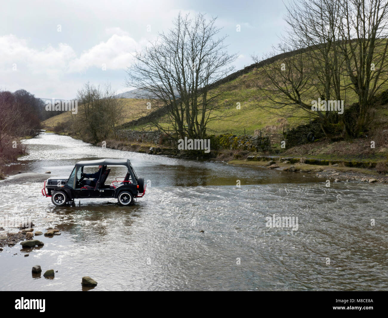 Mini Moke crossing Gayle Beck ford in Gayle near Hawes North Yorkshire UK Stock Photo