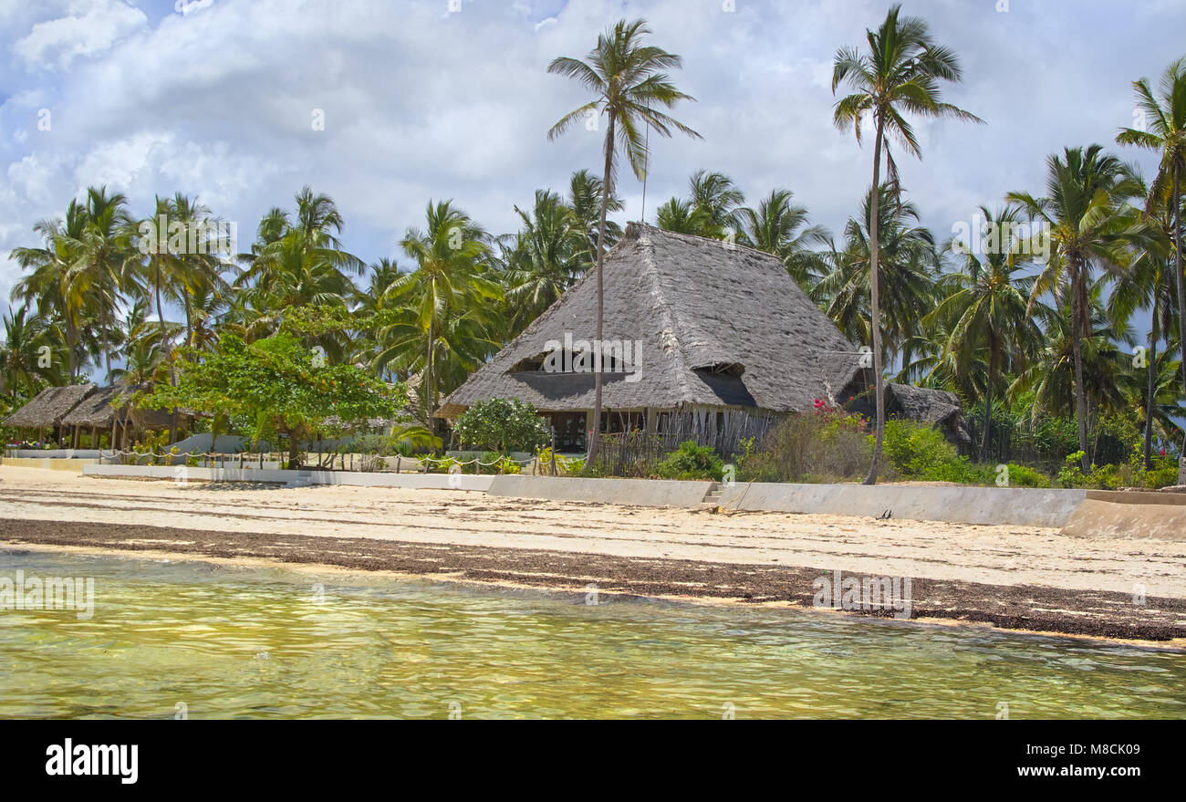 Tropical beach house with coconut palm trees on an island of Zanzibar in Equatorial Africa. Stock Photo