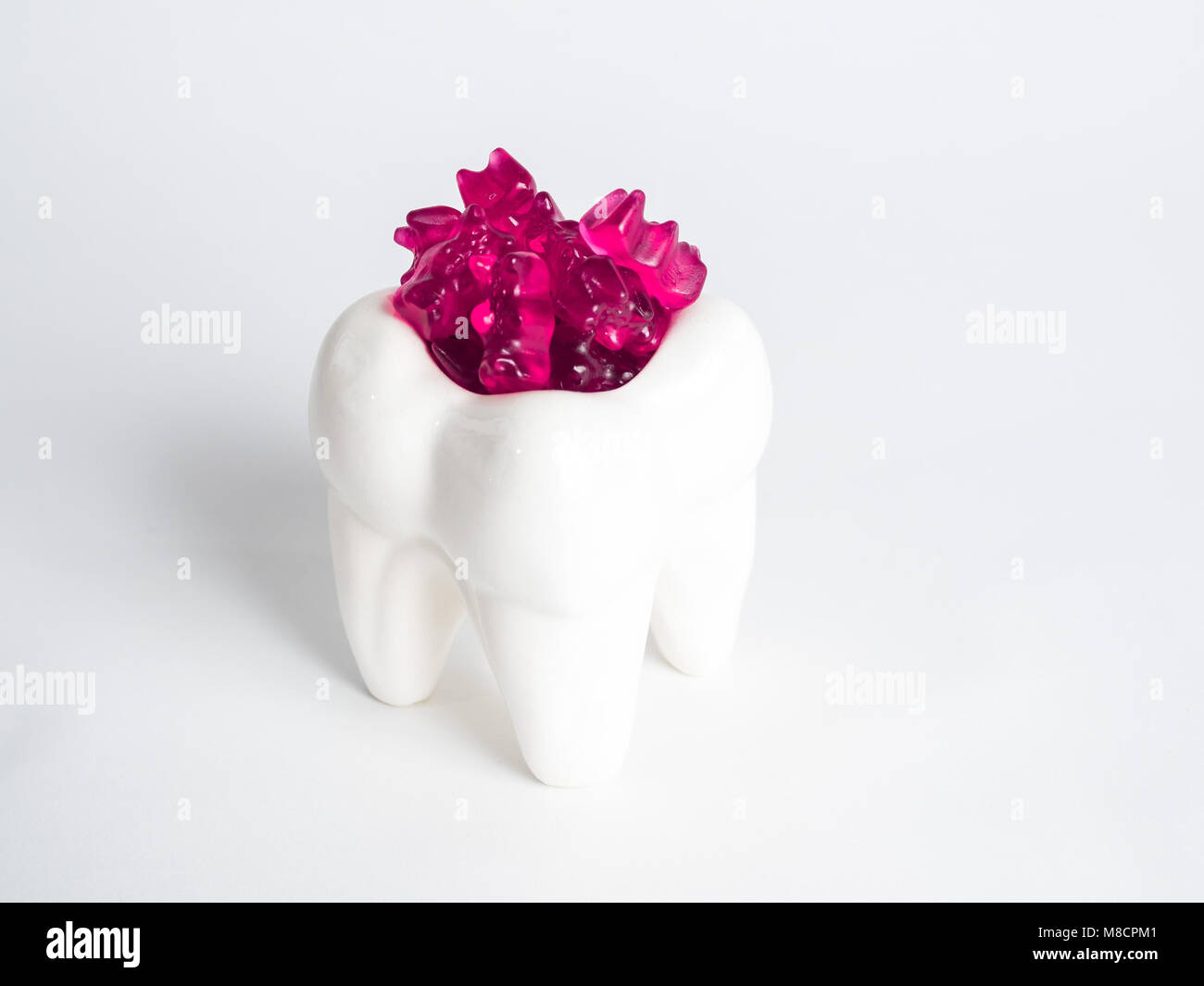 The porcelain tooth is filled with gummy bears Stock Photo
