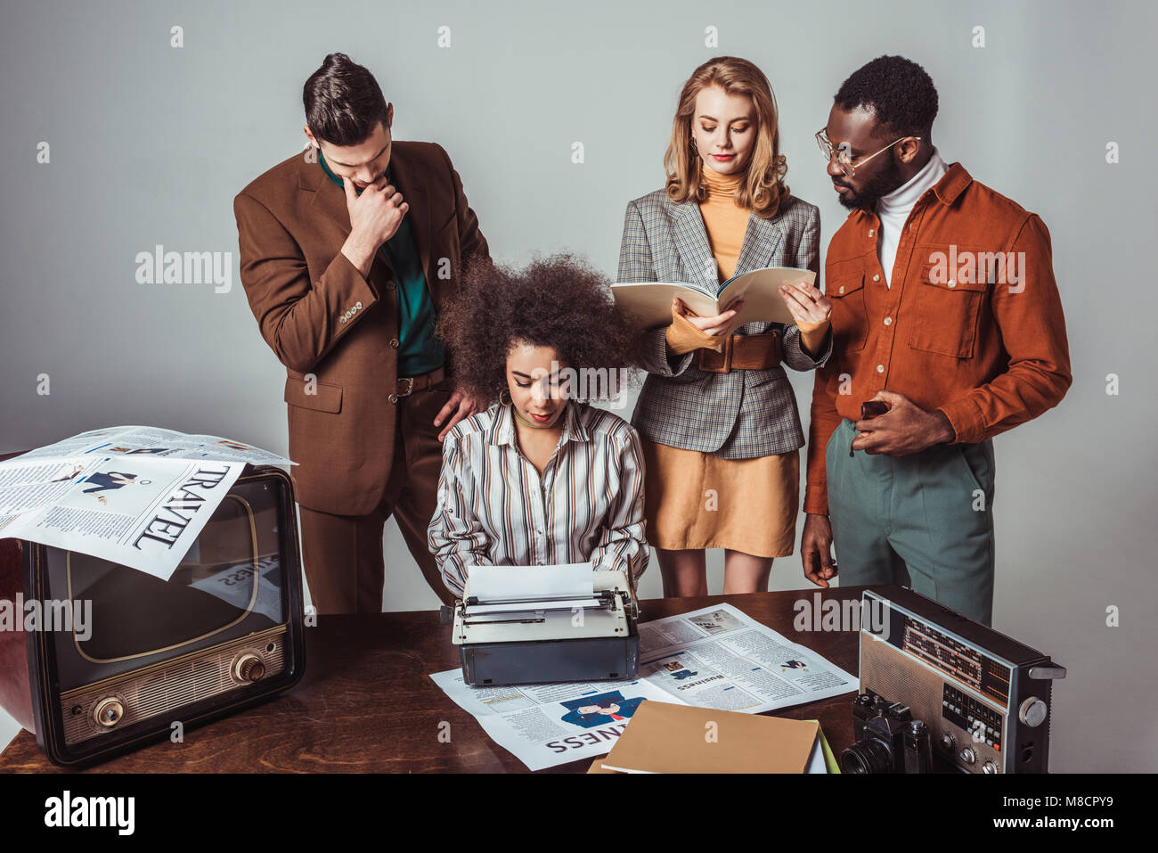 multicultural retro styled journalists at newsroom on grey Stock Photo