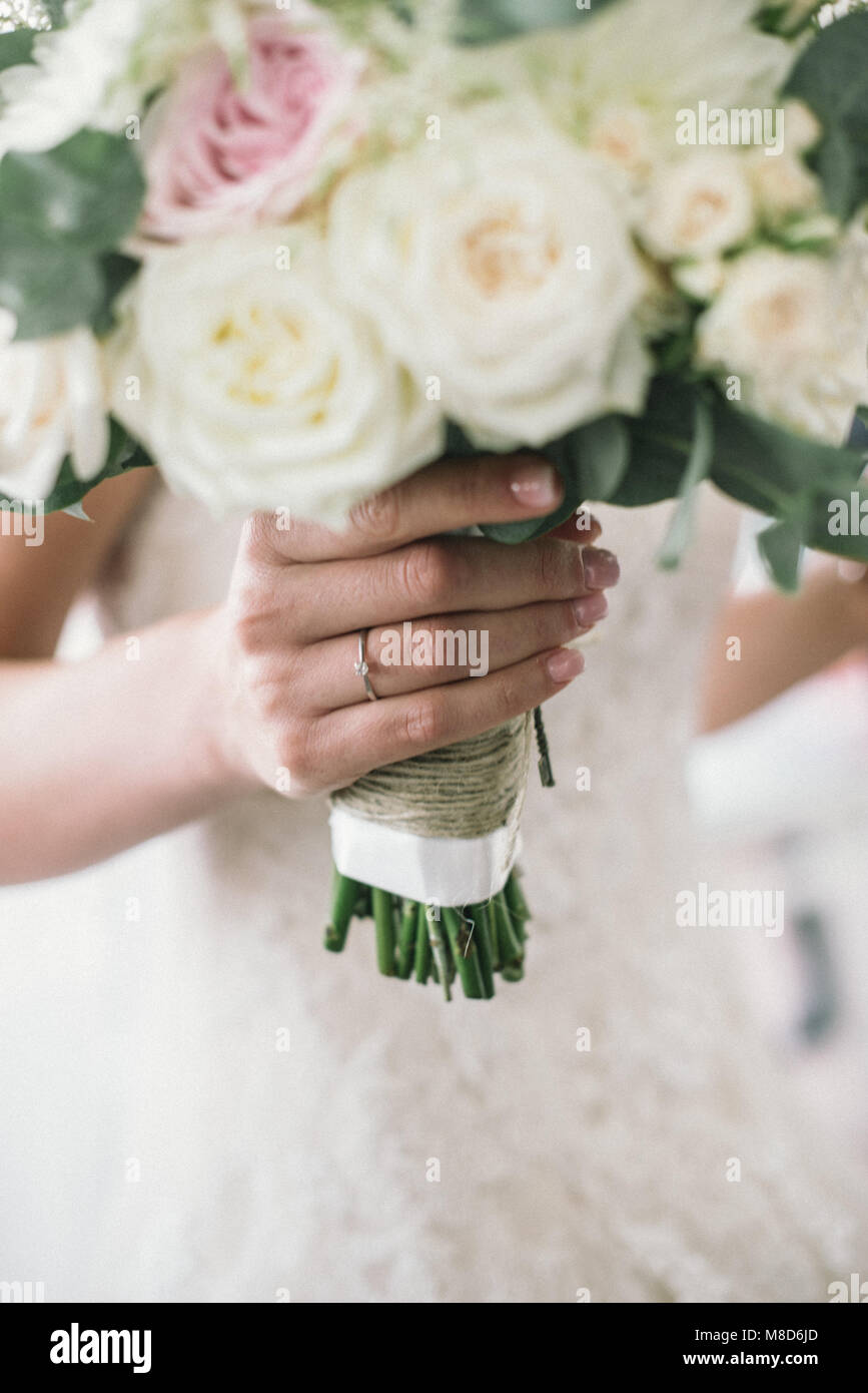 young bride holds in her hands her bouquette of white and pink roses on ...