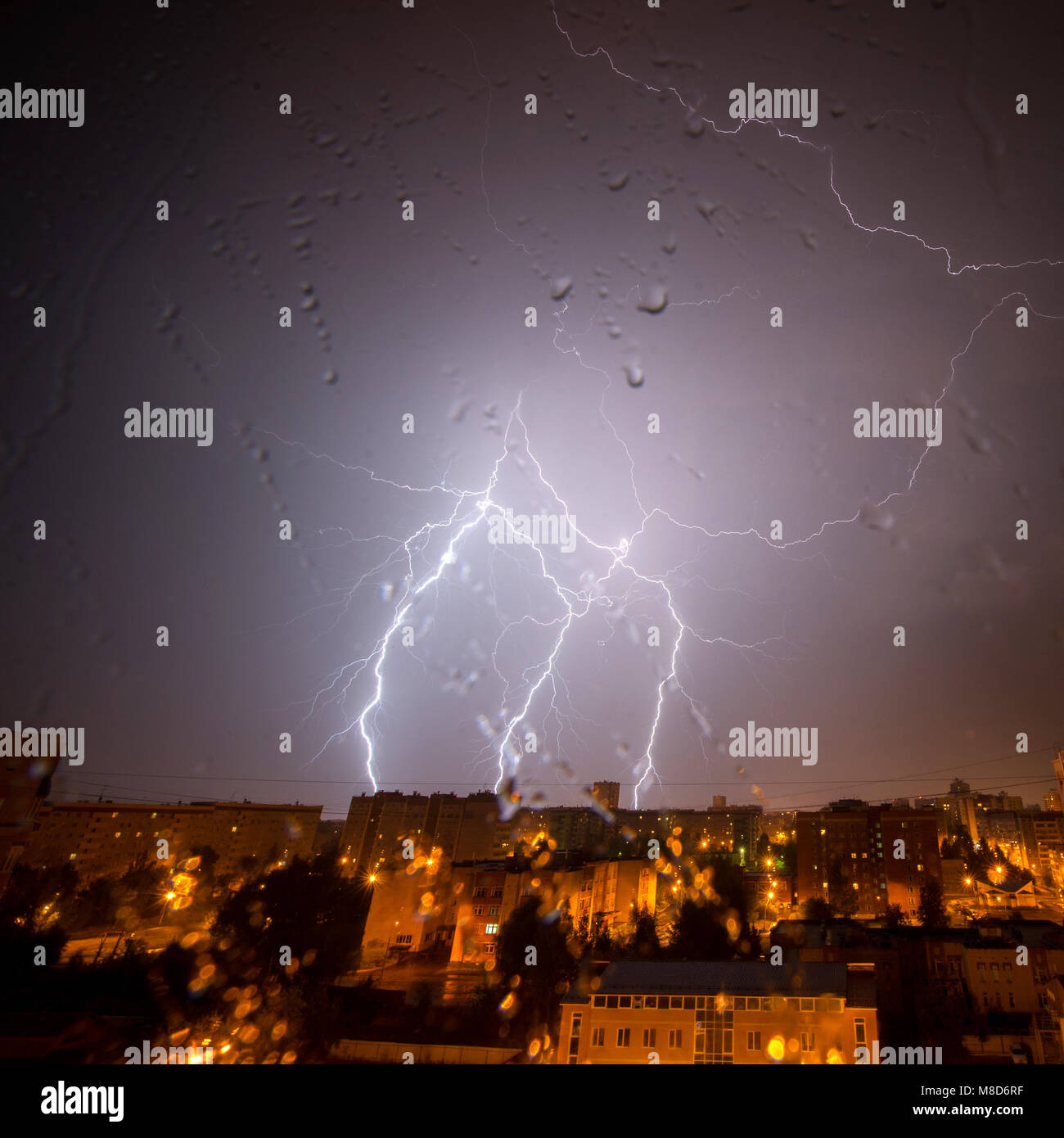 Clouds and thunder lightnings and storm over city. With drops on glass ...