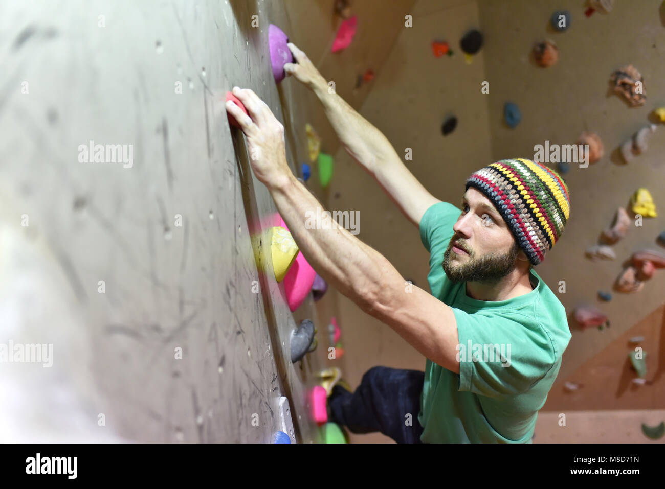 climber bouldering in a sports hall - holding on to the handle of an artificial rock wall Stock Photo