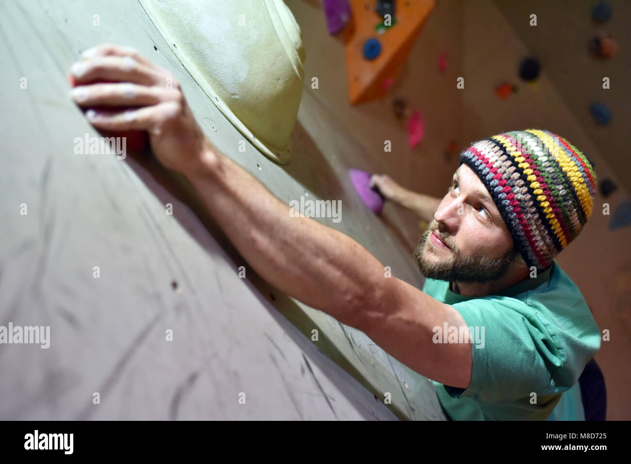 climber bouldering in a sports hall - holding on to the handle of an artificial rock wall Stock Photo