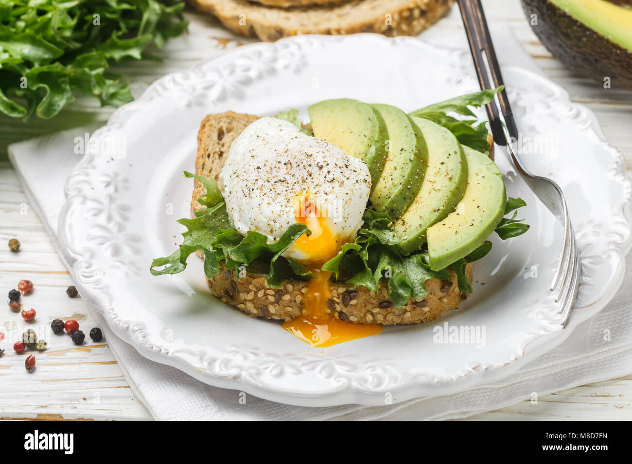 Toast with poached egg, avocado, lettuce, flax seed, spices. Breakfast