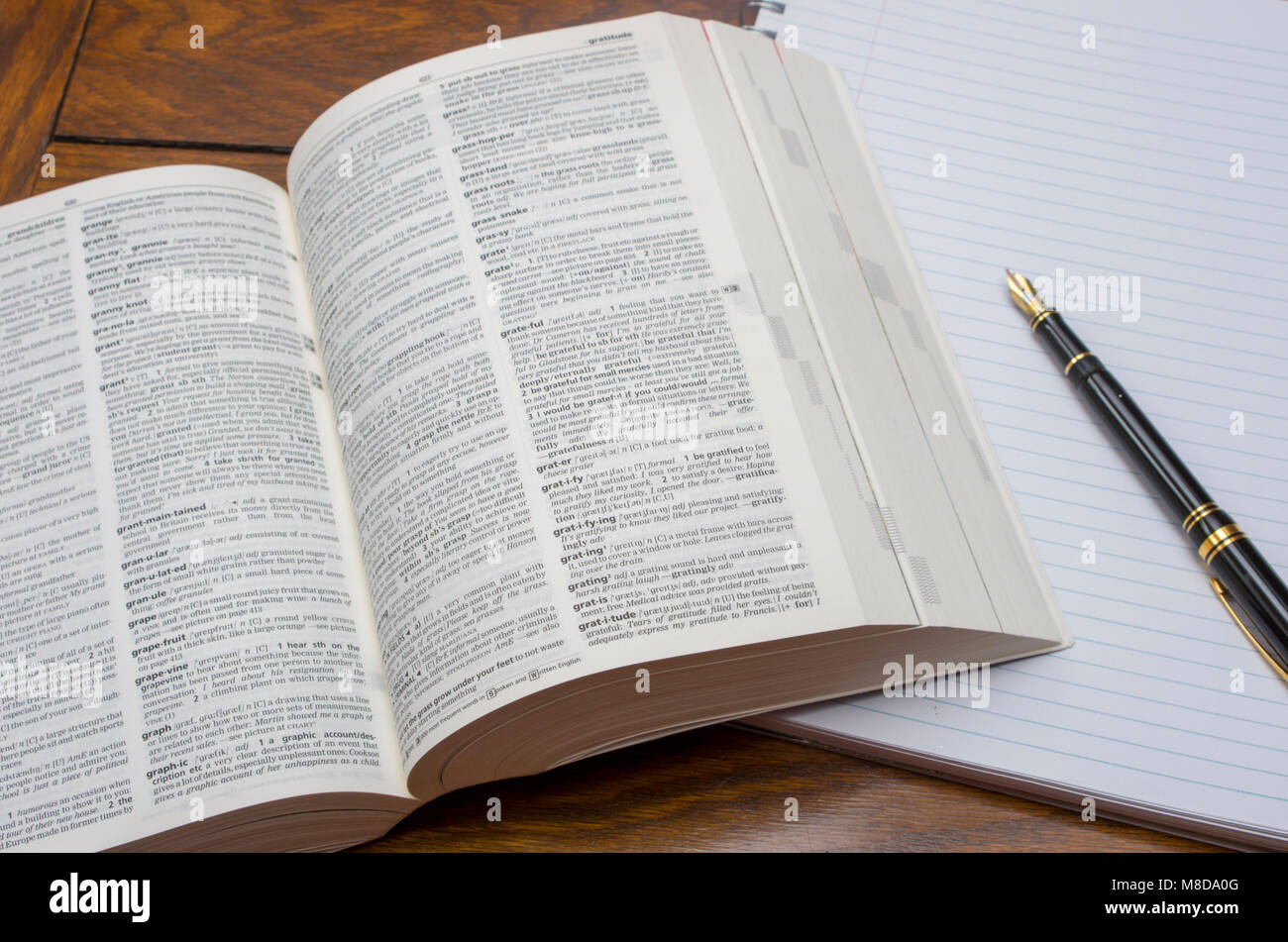 Open copy of Longman Dictionary of Contemporary English with lined pad