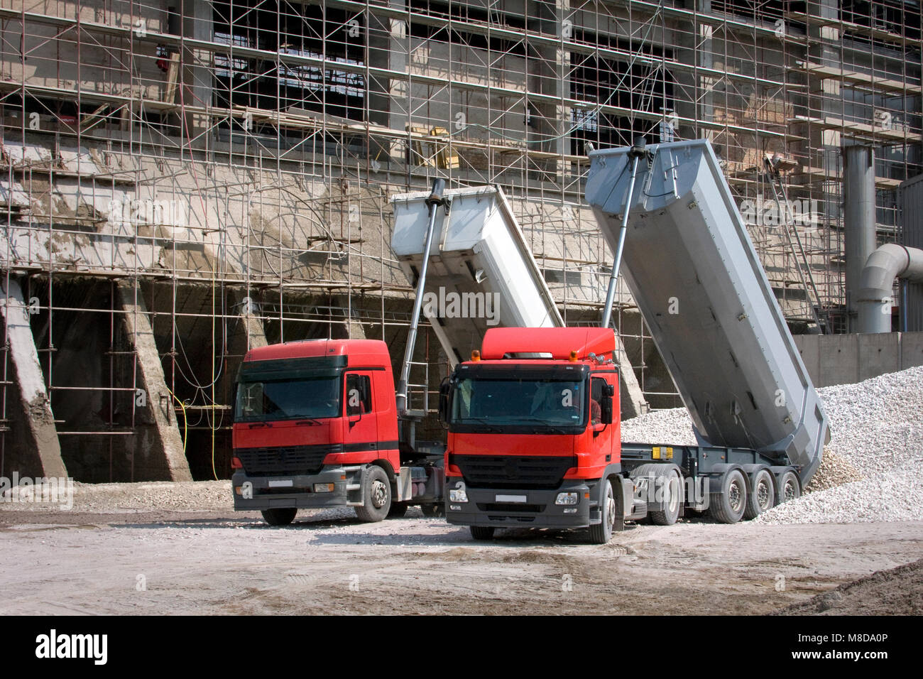 Two big red trucks delivering gravel on construction site Stock Photo ...