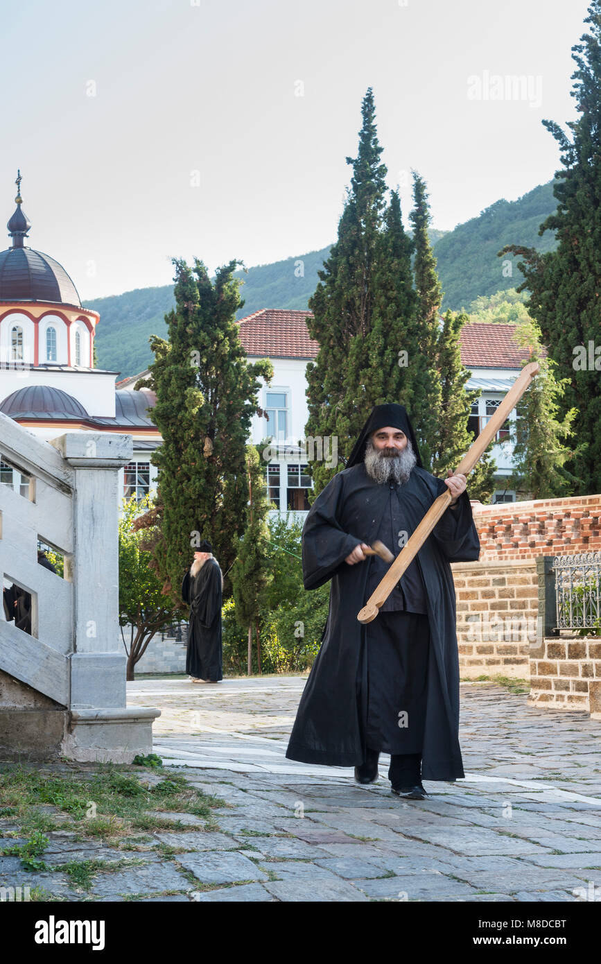 An orthodox monk sounds the call to evening prayer by striking a wooden semantron at the Skete of Saint Andrew at Karyes  on The Athos peninsula, Mace Stock Photo