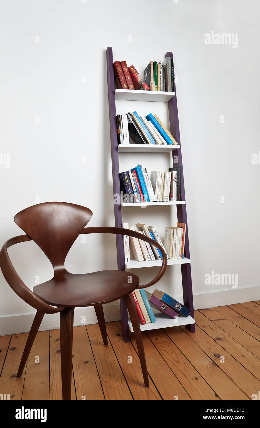 Row of books on a bookshelf and wooden chair Stock Photo