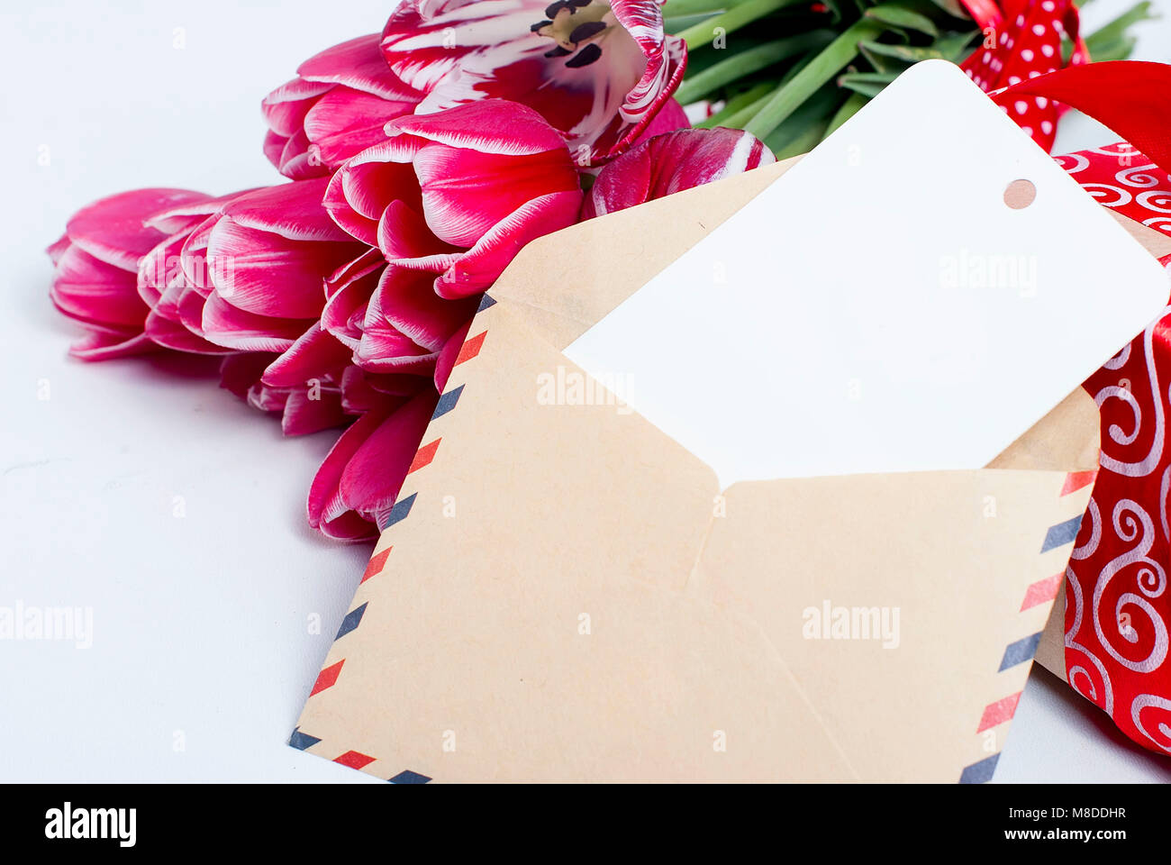 A bouquet of pink tulips in a vase and gift box with red ribbon on a ...