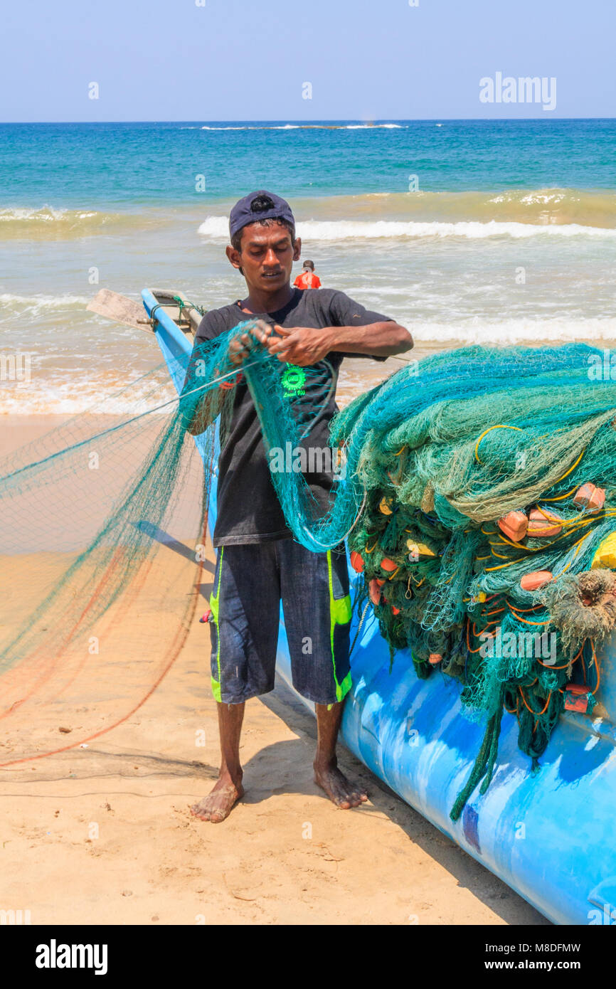 Sri Lankan man folding nets, beach, Colombo, Sri Lanka Stock Photo