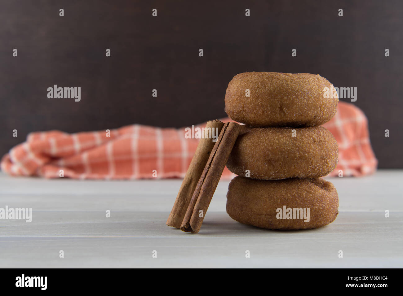 Cinnamon Sticks Leaning Against Donuts in Stack Stock Photo