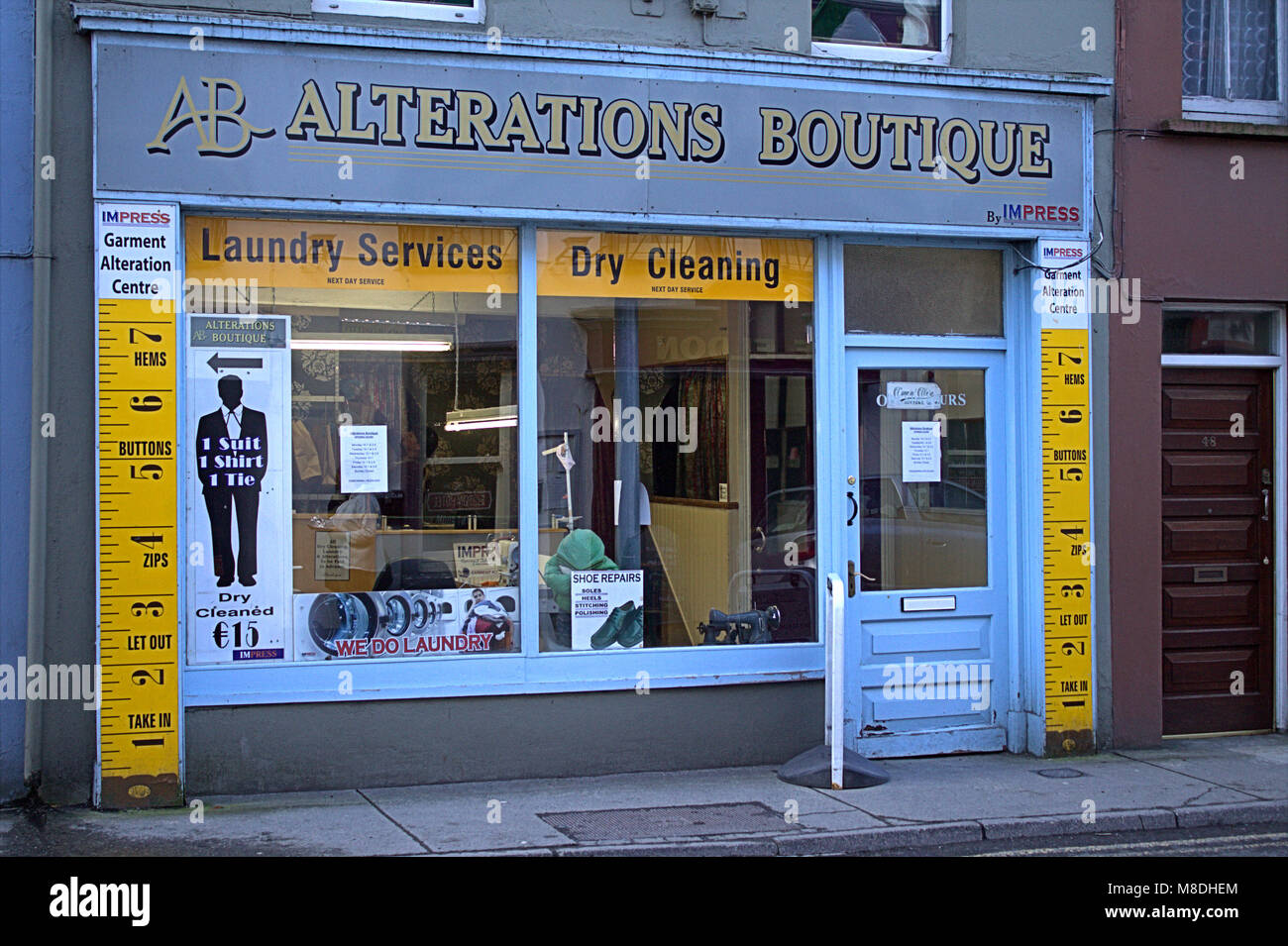 clothing alteration shop window with tape measures up the side of the wall and door .skibbereen, ireland Stock Photo