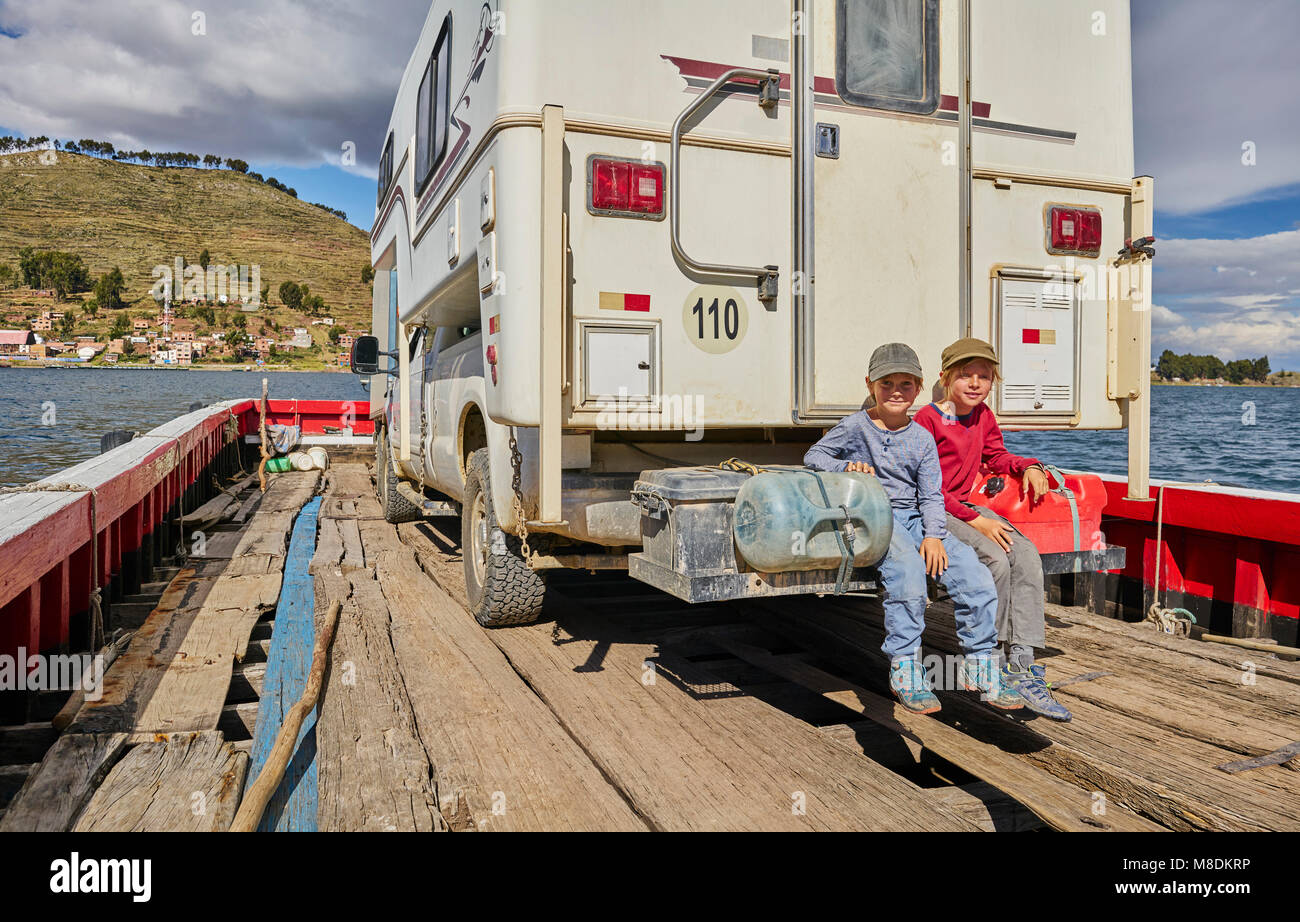 Portrait of two boys sitting at rear of recreational vehicle, on ferry, Tiquina, La Paz, Bolivia, South America Stock Photo