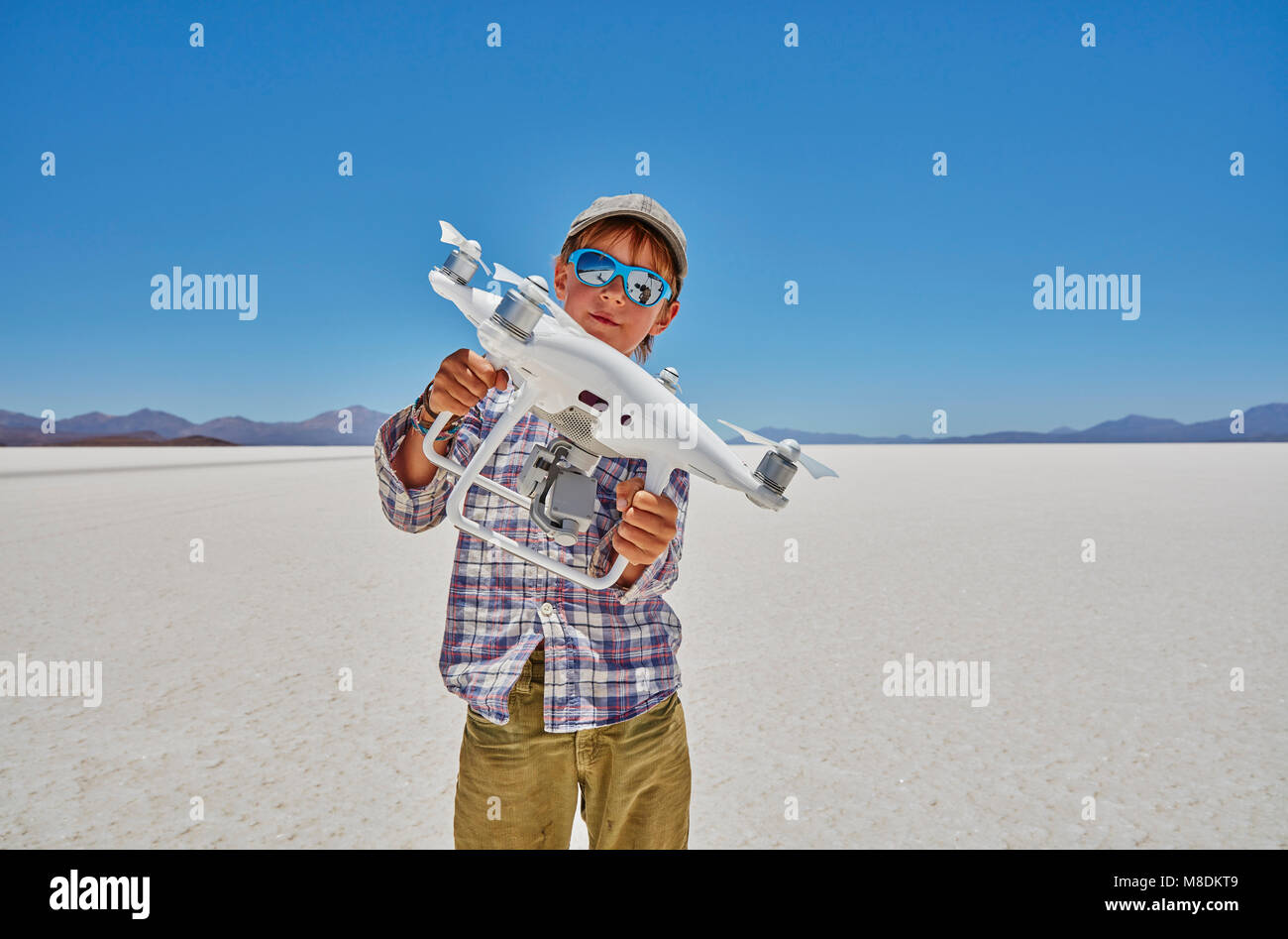 Portrait of boy on salt flats, holding drone, Salar de Uyuni, Uyuni, Oruro, Bolivia, South America Stock Photo