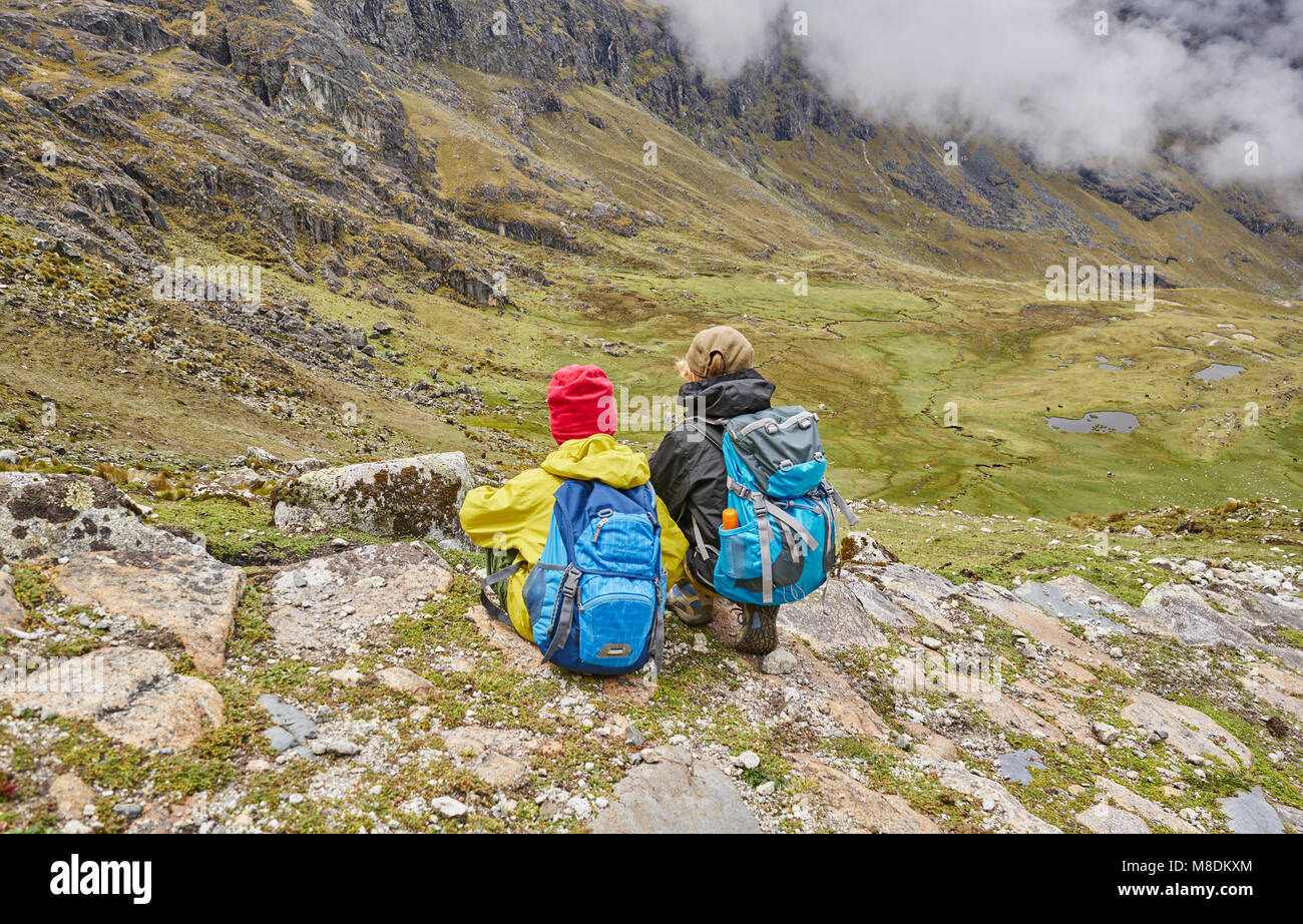 Two boys sitting on hillside, looking at view, rear view, Ventilla, La Paz, Bolivia, South America Stock Photo