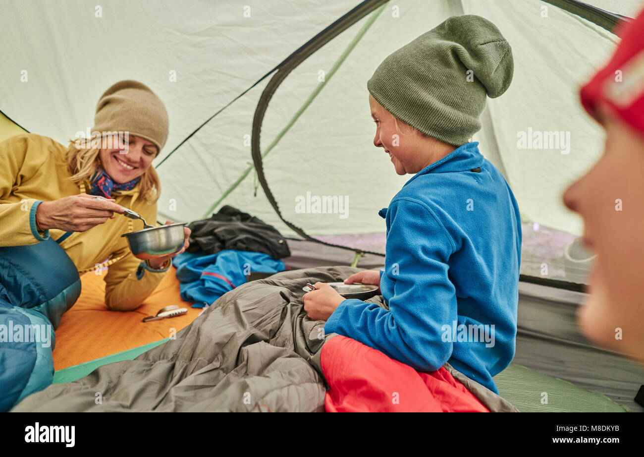 Mother and sons in tent, eating food from bowls, Ventilla, La Paz, Bolivia, South America Stock Photo