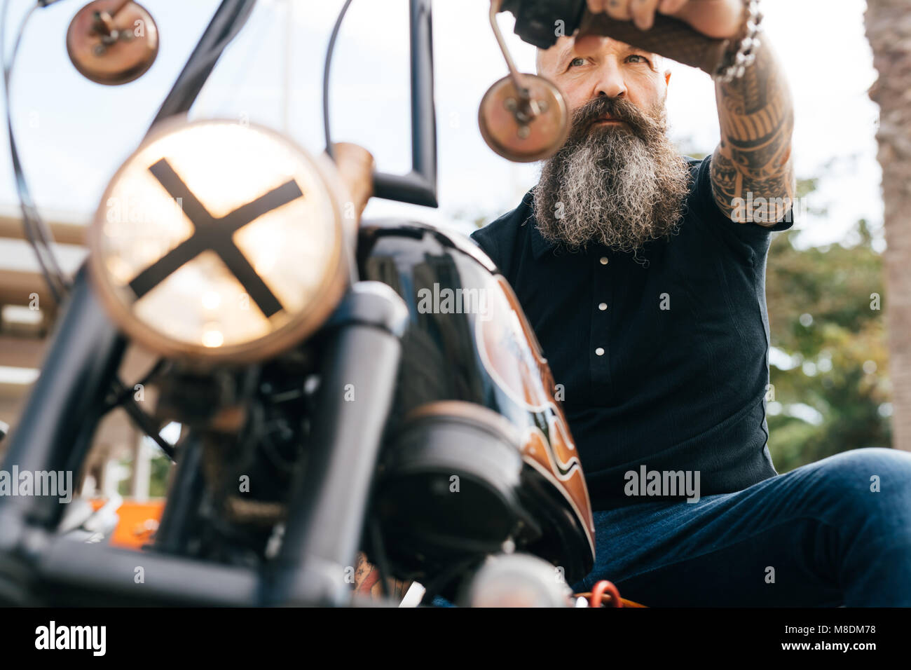 Low angle view of mature male hipster astride motorcycle Stock Photo