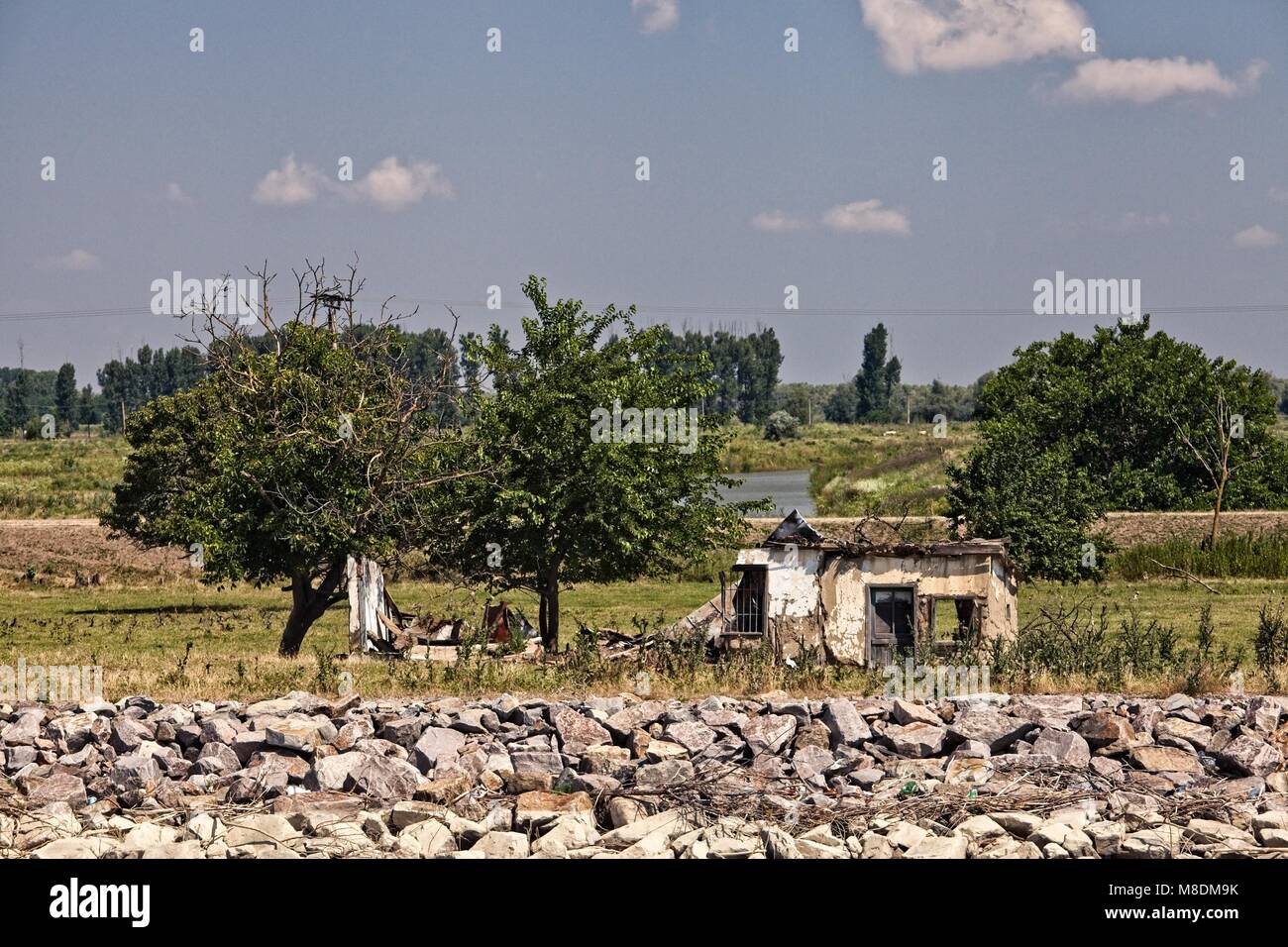 ABANDONED AND RUINED HOUSE AND RIVER BANK FLOOD PROTECTION DOWNSTREAM OF TULCEA ON THE DANUBE RIVER DELTA Stock Photo