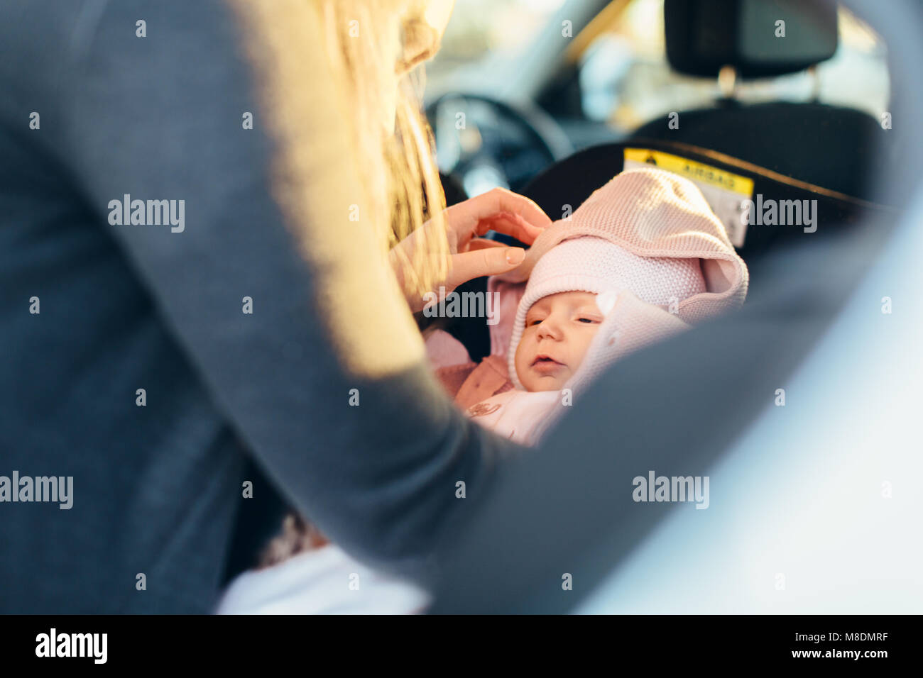 Mother fastening young baby in car seat, mid section Stock Photo