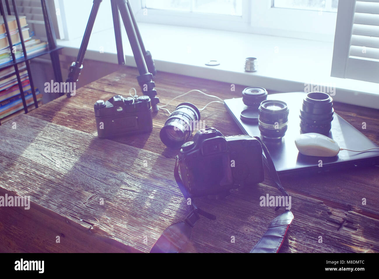 Still life of camera equipment and laptop on table in front of window Stock Photo
