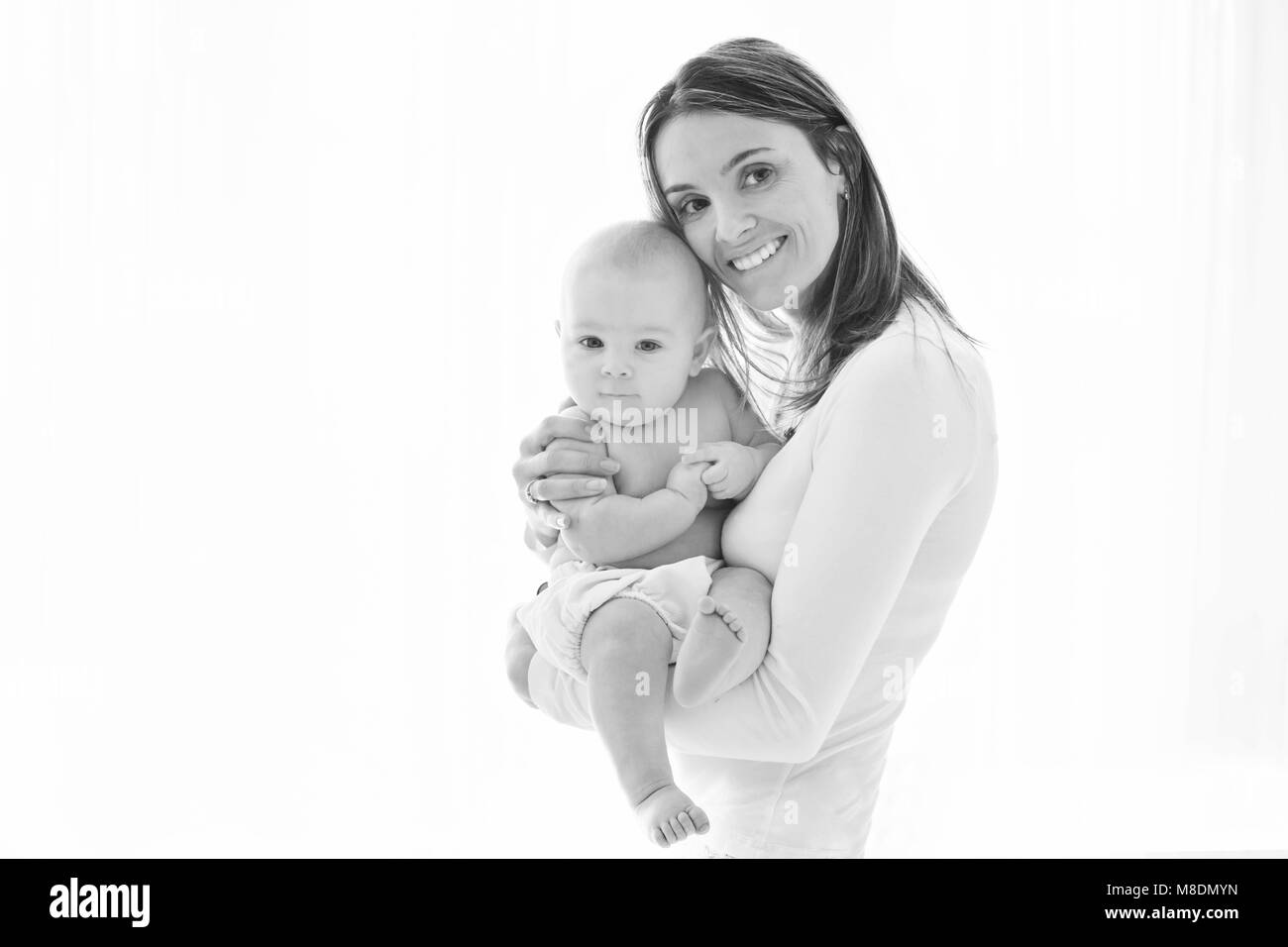 Mother, holding her sick baby boy, sad baby, isolated on white background Stock Photo