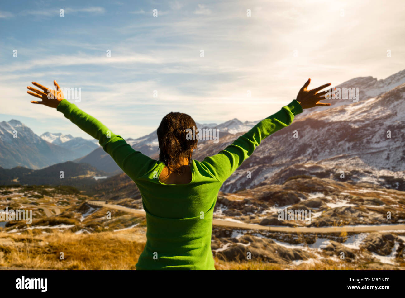 Woman with Arms Outstretched Over Mountain Road With View in Grisons, Switzerland Stock Photo