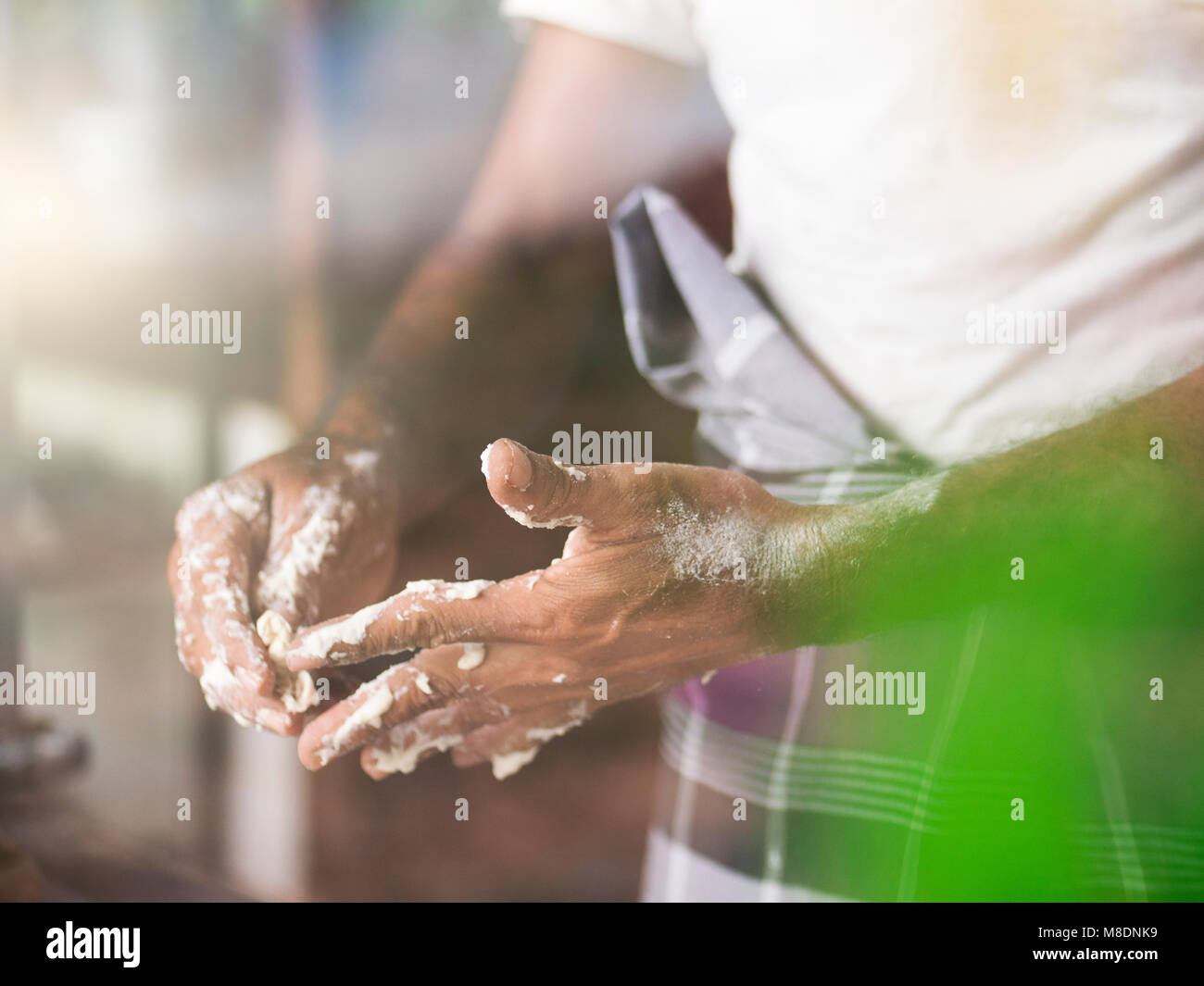 Man removing roti dough from fingers Stock Photo
